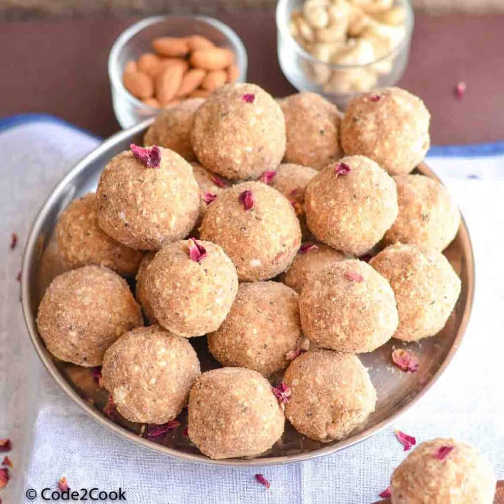 aate ke laddu served in a big plate with cashew almond & wooden spoons.