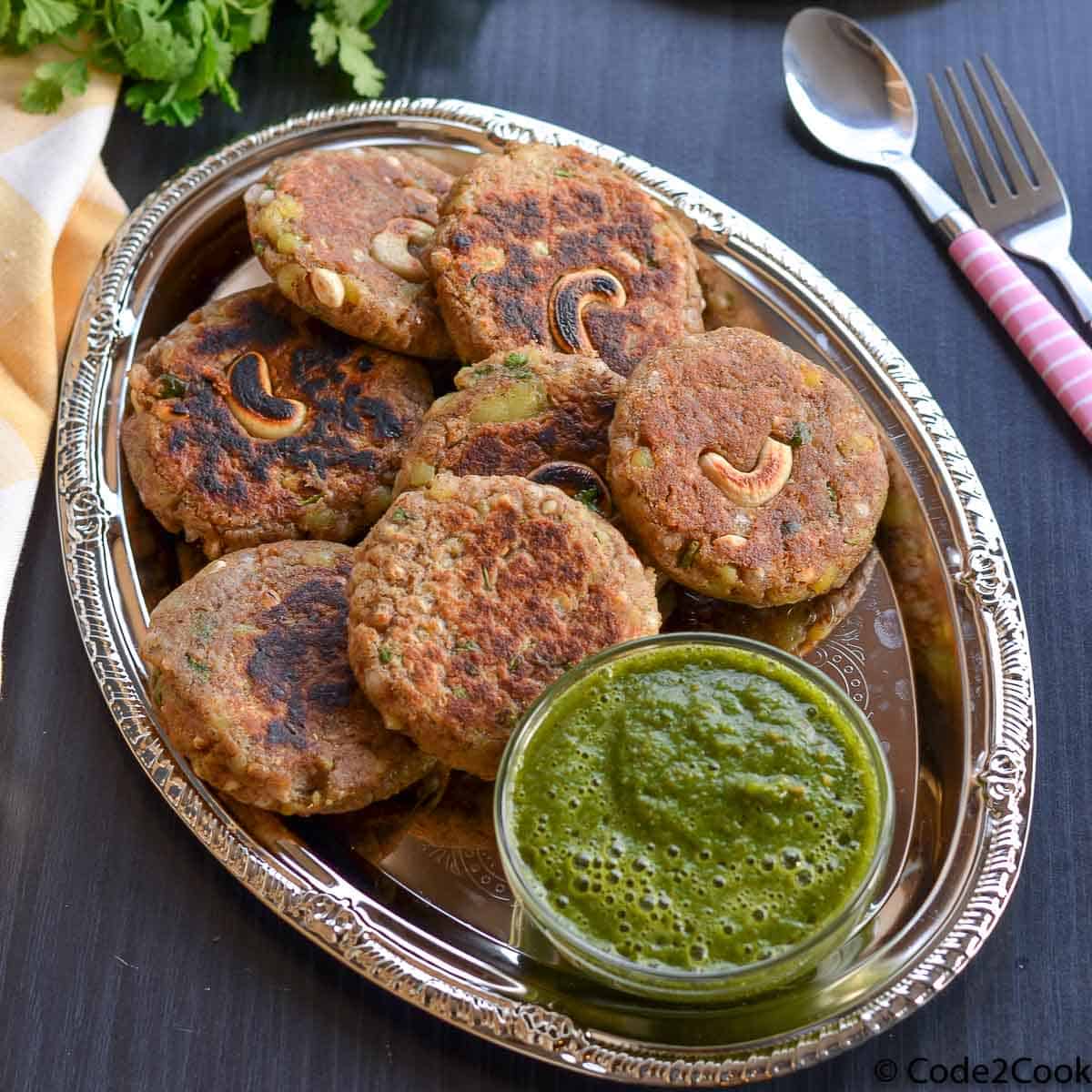 kuttu ki tikki or buckwheat cutlets served with green chutney in a oval shaped plate.