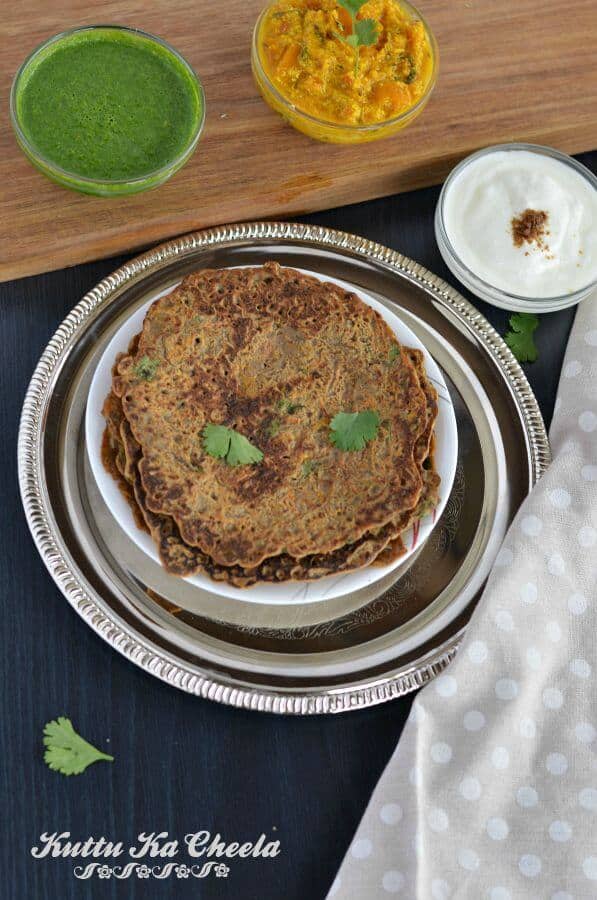 Kuttu ka cheela or falahari cheela served on golden plate with vrat ki chutney, plain curd and vrat ki sabji.