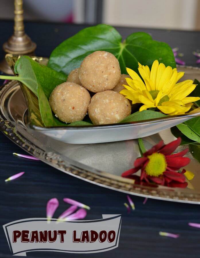 Peanut Ladoo | Peanut Ladoo With Jaggery Recipe Close up click of peanut laddu served in glass plate, surrounded with flowers.