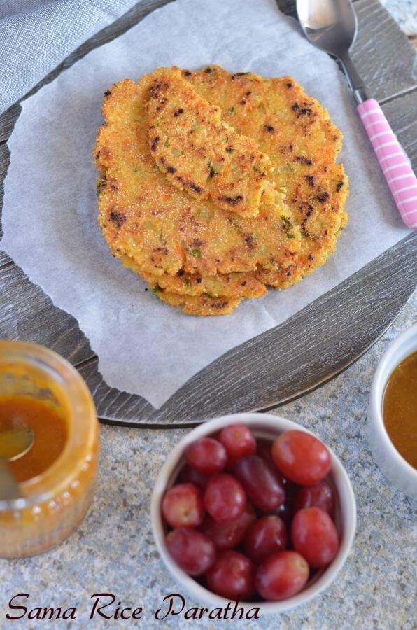 Vrat ka paratha or sama rice paratha is served on a butter paper on a wooden board. Served this with peach chutney and grapes.