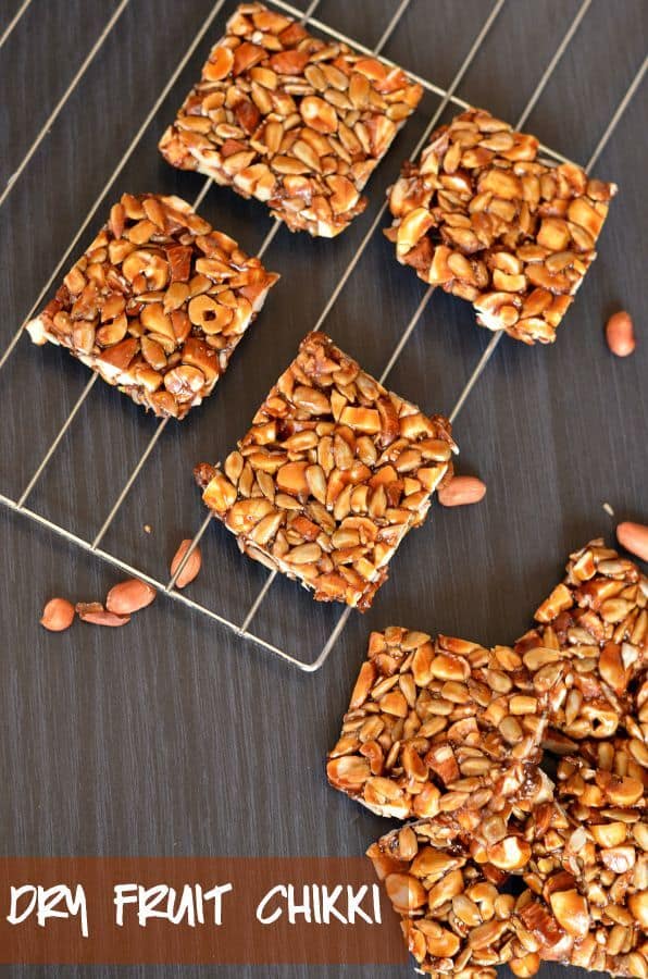 Dry Fruit Chikki | Peanut Chikki | Mixed Nut Chikki dry fruit chikki or mixed nut brittle bar is placed on rack, close up from above. Peanuts are scattered around.