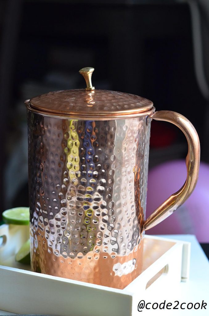 copper pitcher is kept in wooden tray with lid