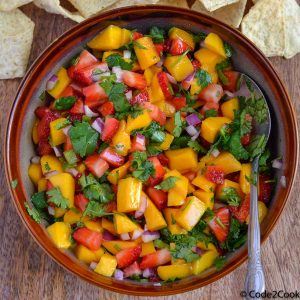strawberry mango salsa is served in brown bowl with tortilla strips.