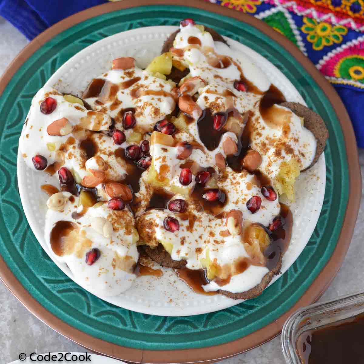 buckwhear crackers are served in a green plate with curd, chutne, potato, pomegranate and boiled potato.