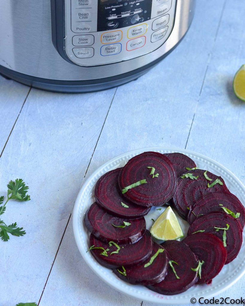 Steamed beets are sliced and served in white glass plate. Garnished with chopped coriander & lemon wedge.