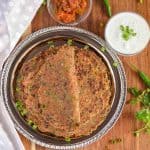 sprin onion paratha served in a plate along with curd and pickle.