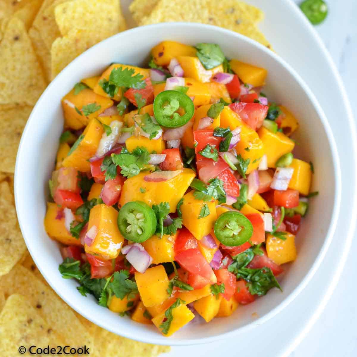 a close up click of mango salsa served in white bowl