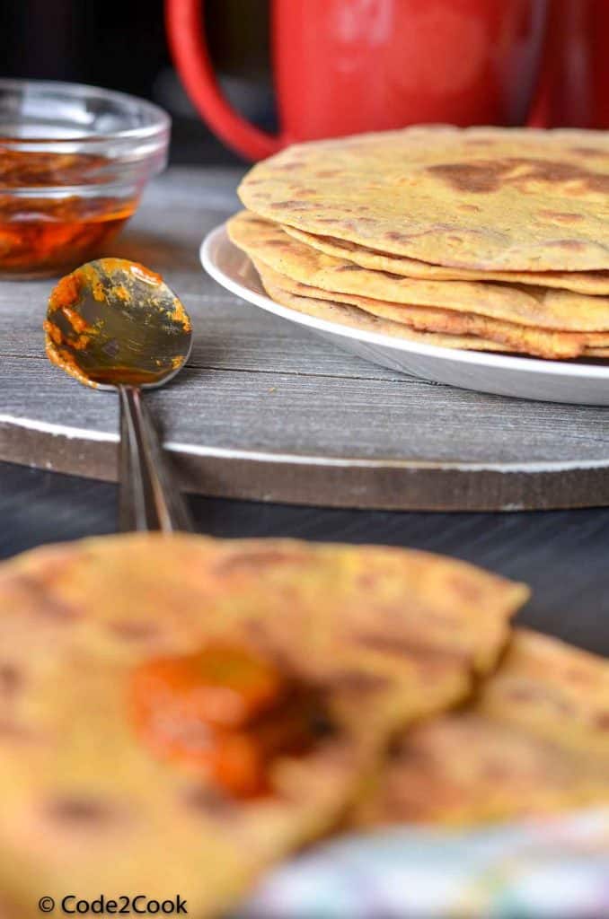 stacked khakhras on a wooden board with pickle and tea cup