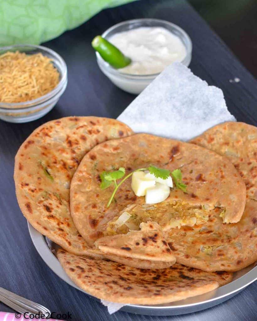 Parathas are spread on a big plate with curd & namkeen.
