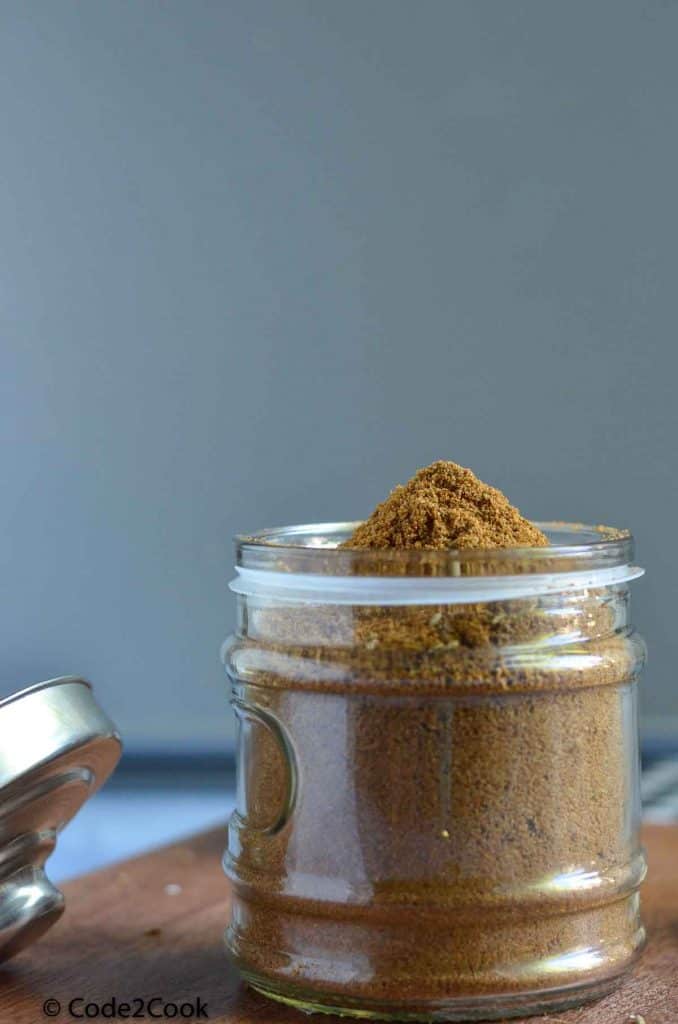 ground cumin in in a glass jar, kept on a wooden board.