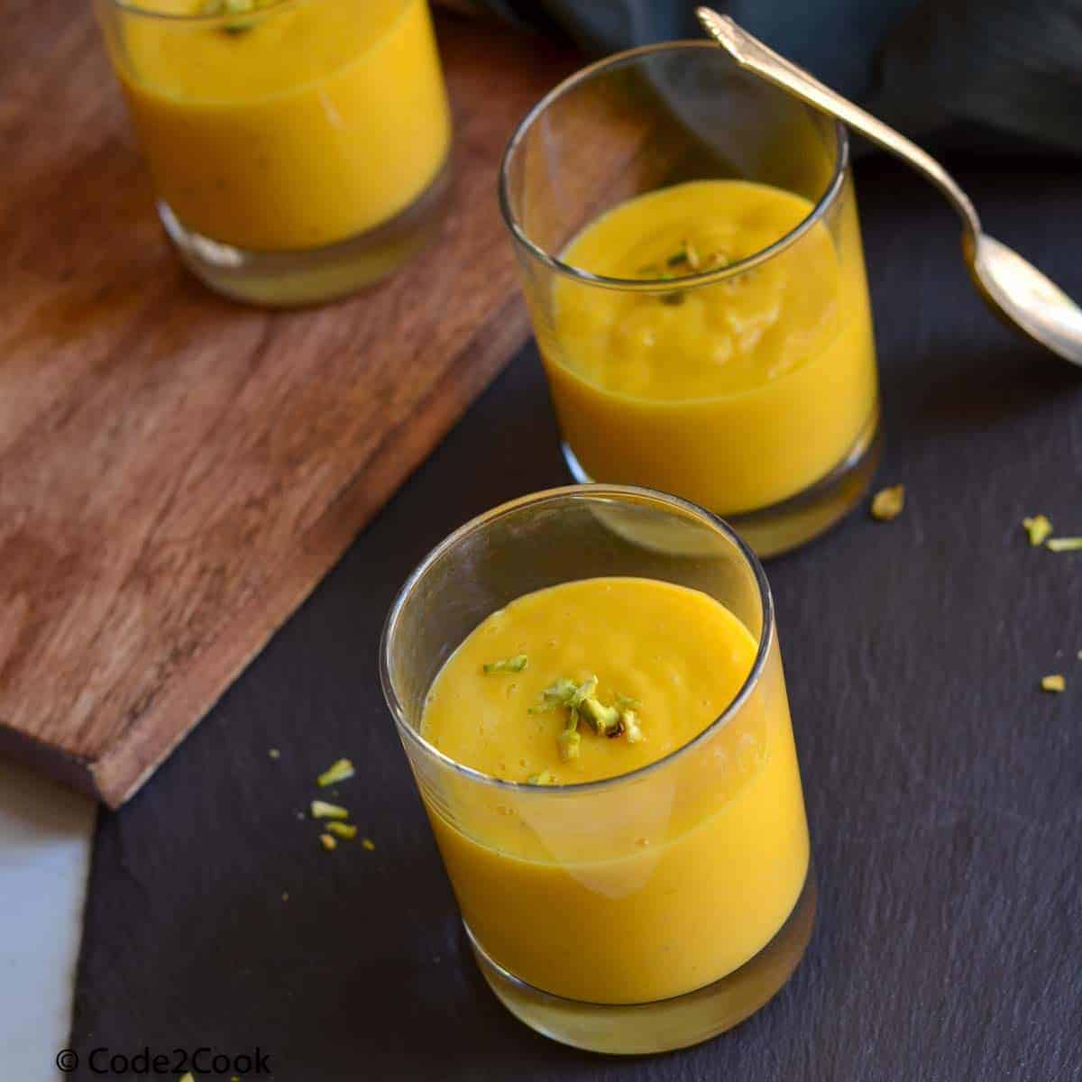 Aamras served in three small glasses and garnished with chopped nuts