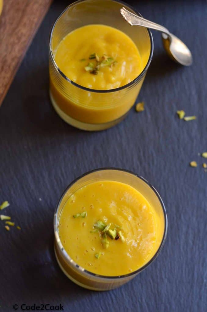 aamras served in glass and garnished with chopped nuts.