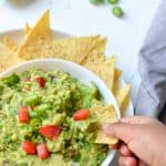 scooping simple guacamole with nacho