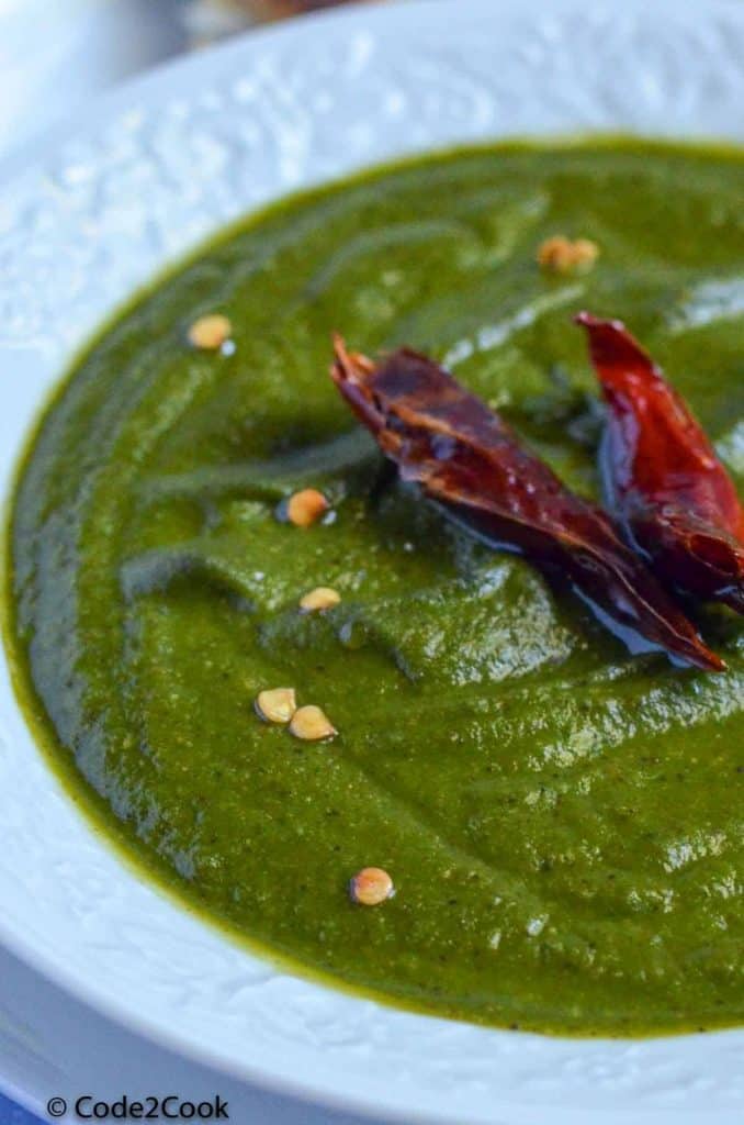 A close up click of palak chutney with dry red chili tempering